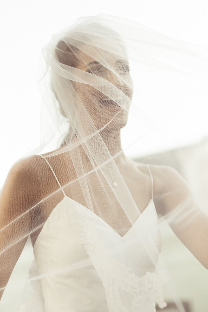 Happy bride playing in veil on wedding day