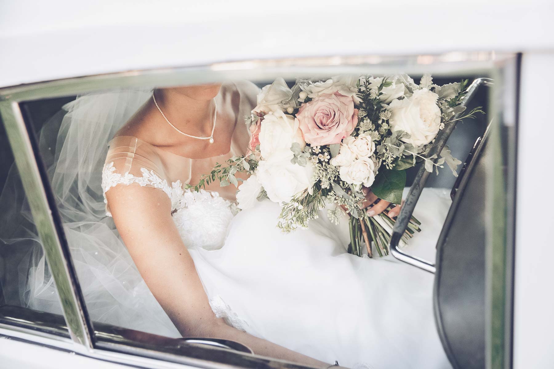 Bride arriving to wedding in Rolls Royce with bouquet