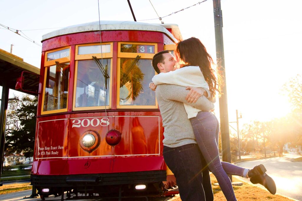 Couple embraces in front of red streetcar in New Orleans