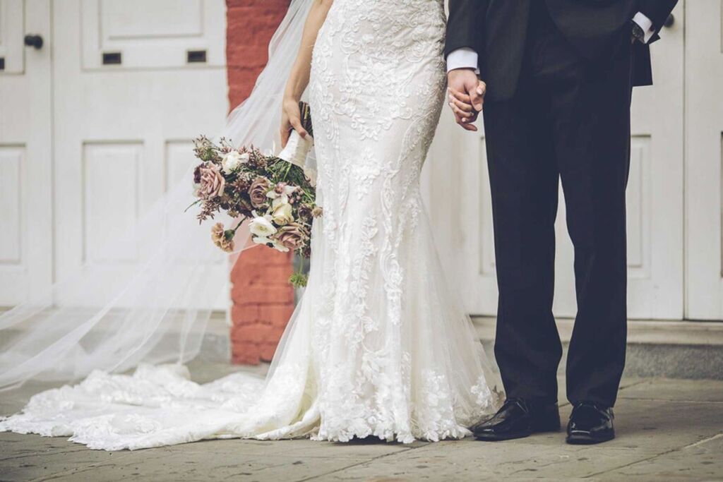 wedding bouquet and wedding dress and tux on bride and groom